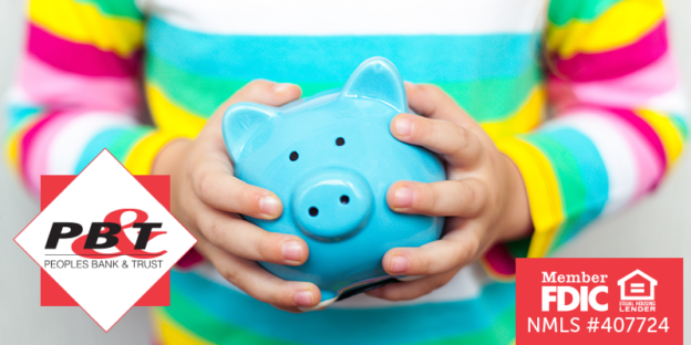 A child's hands holding a blue piggy bank with their colorful striped shirt in the background